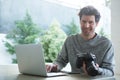 Man using laptop and holding digital camera Royalty Free Stock Photo