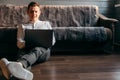 Man is using a laptop while lying on sofa in living room Royalty Free Stock Photo