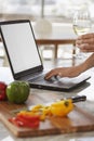 Man Using Laptop Next To Chopped Bellpepper In Kitchen Royalty Free Stock Photo