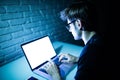 Man using laptop in the night with white screen. Young hacker work on laptop in the night