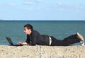 Man using laptop and phone at beach Royalty Free Stock Photo