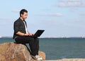 Man using laptop and phone at beach Royalty Free Stock Photo