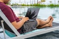 Man using laptop while sitting on chair at swimming pool Royalty Free Stock Photo