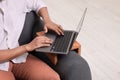 Man using laptop on sofa armrest wooden table at home, closeup