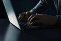 Man using laptop at table on dark background. Criminal activity Royalty Free Stock Photo