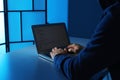 Man using laptop at table in dark room. Criminal offence Royalty Free Stock Photo