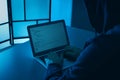 Man using laptop at table in dark room. Criminal offence Royalty Free Stock Photo