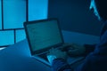 Man using laptop at table in dark room. Criminal offence Royalty Free Stock Photo