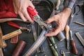 Man using leather punch while working with belt at factory, closeup