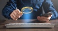 Man using magnifying glass over computer keyboard. Concept of searching internet Royalty Free Stock Photo