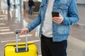 Man using mobile phone at airport. Urban traveler wearing casual holds smartphone, guy texting message while holding Royalty Free Stock Photo