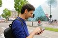 Man using mobile phone app in modern urban city street. Young caucasian man holding smartphone for business work.