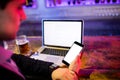 Man using mobile phone with glass of beer and laptop on table at bar counter Royalty Free Stock Photo