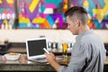 Man using mobile phone with laptop on table at bar counter Royalty Free Stock Photo