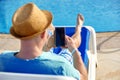 Man using mobile phone on vacation by the pool in hotel, concept of a freelancer working for himself on vacation and Royalty Free Stock Photo