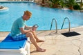 Man using mobile phone on vacation by the pool in hotel, concept of a freelancer working for himself on vacation and Royalty Free Stock Photo