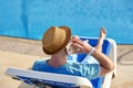 Man using mobile phone on vacation by the pool in hotel, concept of a freelancer working for himself on vacation and Royalty Free Stock Photo