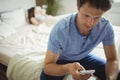 Man using mobile phone while woman sleeping on bed Royalty Free Stock Photo