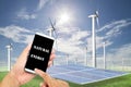 man using mobile smart phone control with Solar panels,wind turbines on green grass with blue sky background,natural Energy Royalty Free Stock Photo