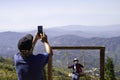 Man using mobilephone camera making photo to woman sitting on swing on nature background in holiday vacation time.  Asian woman an Royalty Free Stock Photo