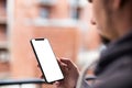 Man using modern mobile smartphone bezel less design. Shot with third-person view, blank screen.