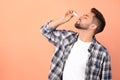 Man using nasal spray on peach background, space for text