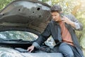 Man using phone for contact maintenance car service. Traveler sitting and using smartphone while Broken car