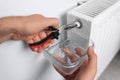 Man using pliers while preparing heating radiator for winter season, closeup