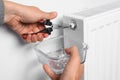 Man using pliers while preparing heating radiator for winter season, closeup