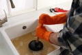 Man using plunger to unclog sink drain in kitchen