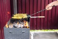 A man using a poker straightens the coals in the grill