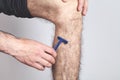 Man using razor to remove hair on leg