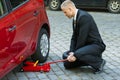 Man using red hydraulic floor jack for car repairing