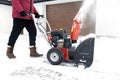 Man using red snowblower machine outdoor. Removing snow near house from yard