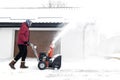 Man using red snowblower machine outdoor. Removing snow near house from yard Royalty Free Stock Photo