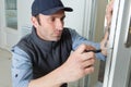 Man using screwdriver to adjust door hinge Royalty Free Stock Photo