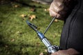 Man using screwdriver to attach a grabber attachment to a long pole outdoors with grass and fall leaves in background - closeup of