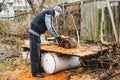 A man using a small chainsaw to cut wood outdoors, suggesting woodworking or DIY projects Royalty Free Stock Photo