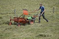a man using a small tractor to pull hay behind it