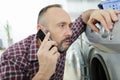 man using smart phone while doing laundry