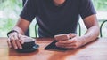 A man using smart phone and holding coffee cup on wooden table Royalty Free Stock Photo