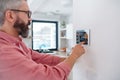 Man using smart thermostat, adjusting, lowering heating temperature at home. Concept of sustainable, efficient, and Royalty Free Stock Photo