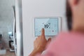 Man using smart thermostat, adjusting, lowering heating temperature at home. Concept of smart technology and thermostats Royalty Free Stock Photo