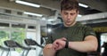 Man using a smart watch in gym. Sportive man checking pulse in smartwatch after gym workout, fitness technology. Sports