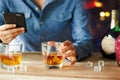 Man using smartphone while drinking whiskey alcohol beverage a