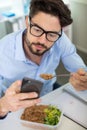 man using smartphone while eating meal in workplace Royalty Free Stock Photo
