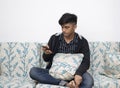 Man is using a smartphone for the internet while relaxed sitting on the sofa at his modern home Royalty Free Stock Photo