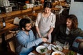 Man using smartphone while paying restaurant bill with contactless payment during dinner with friends