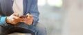 A man using smartphone while sitting on sofa at hotel lobby with blurred background Royalty Free Stock Photo