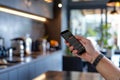A man is using a smartphone while standing in a kitchen, Enable remote access and control through a mobile app for convenience and Royalty Free Stock Photo